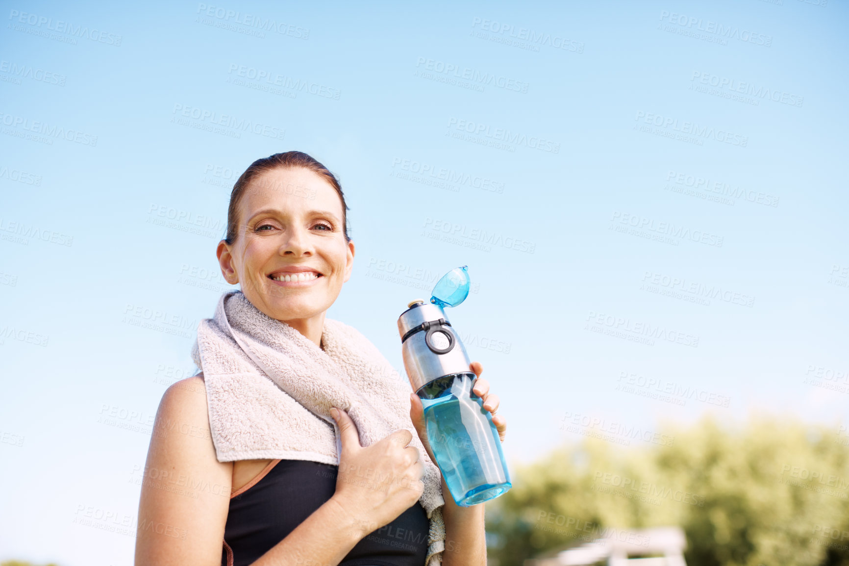 Buy stock photo An attractive woman standing with her water bottle after an outdoor workout