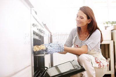 Buy stock photo A mature woman removing scones from the oven