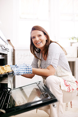 Buy stock photo Portrait of a mature woman removing scones from the oven