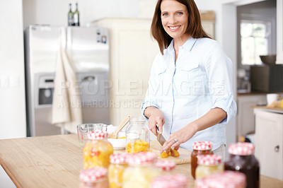 Buy stock photo Portrait of a mature woman cutting peaches in the kitchen