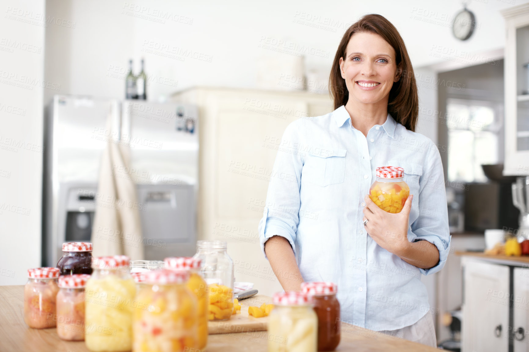 Buy stock photo Portrait of a mature woman standing with a jar in the kitchen