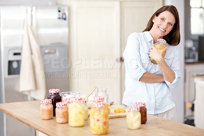 Buy stock photo A mature woman holding a jar to her chest in the kitchen