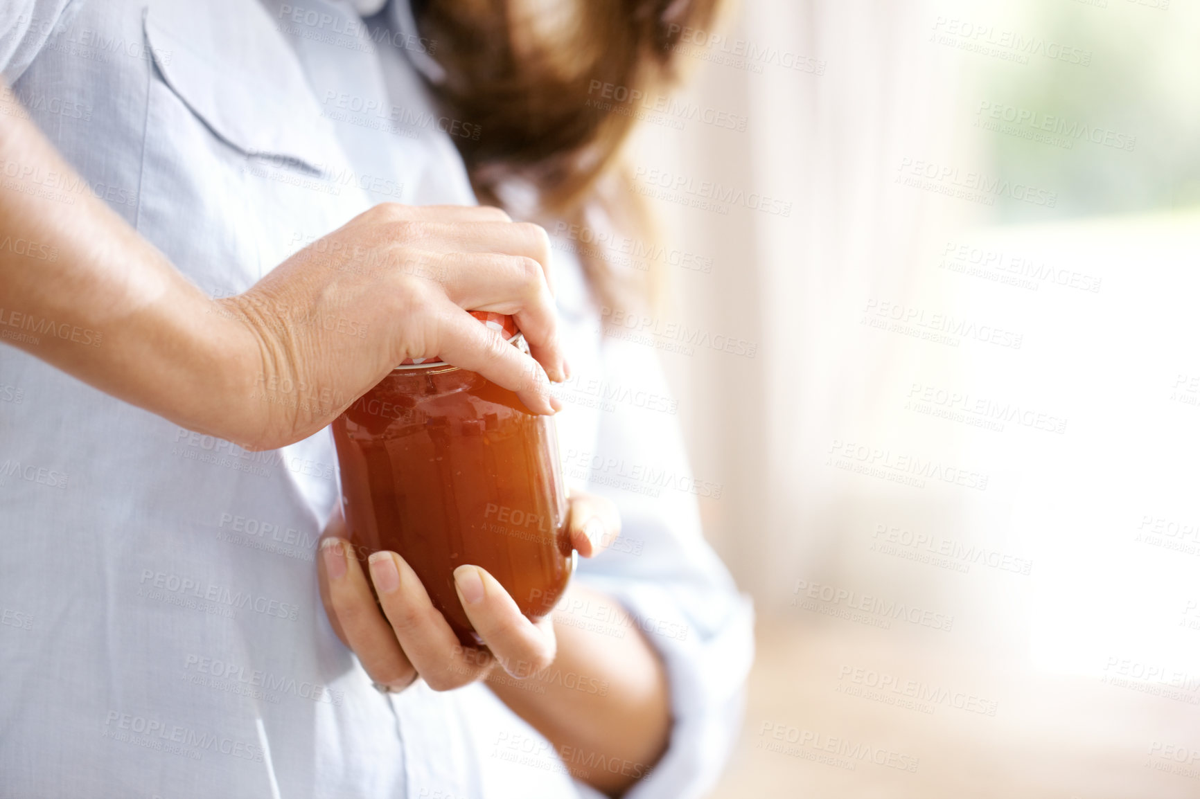 Buy stock photo Cropped image of a woman trying to open a jar in the kitchen