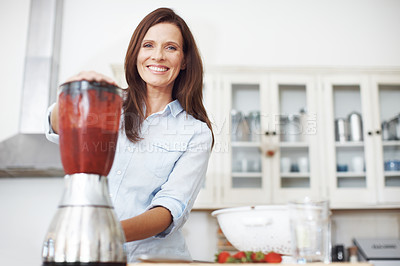 Buy stock photo An attractive woman using a blender to make a fruit smoothie
