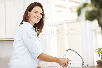 Buy stock photo Portrait of an attractive woman washing her hands by the kitchen sink