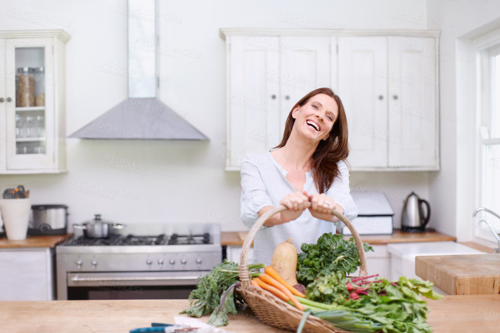 Buy stock photo Portrait, woman and vegetables on kitchen table with laughing, pride and home with greens in basket. Female person, organic produce and nutrition for diet, healthy food or sustainability in house