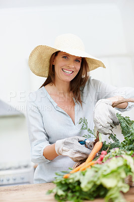 Buy stock photo A beautiful woman cuts the stems off her freshly picked vegetables while looking at the camera