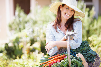 Buy stock photo A beautiful woman in a straw hat holding a basket of vegetables in her garden