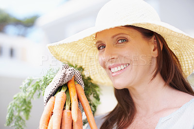 Buy stock photo Portrait of a beautiful woman in a straw hat holds up a bunch of carrots while smiling at the camera