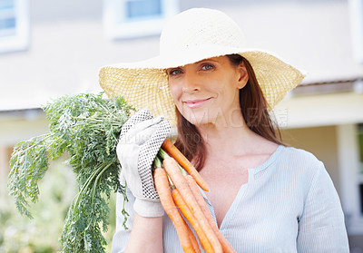 Buy stock photo Portrait of a beautiful woman, wearing a straw hat and gardening gloves, holding up a bunch of carrots