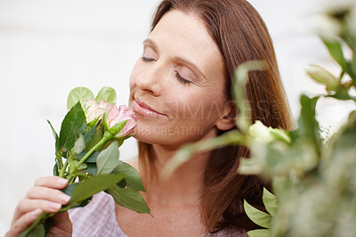 Buy stock photo A beautiful woman smelling roses from a fresh bouquet of flowers