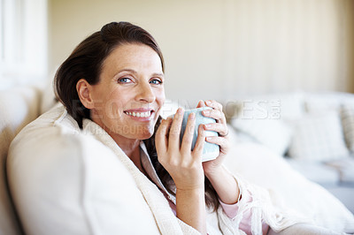 Buy stock photo Portrait of an attractive woman enjoying a cup of coffee while sitting on a sofa indoors