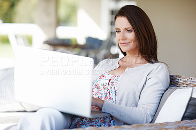 Buy stock photo An attractive woman working on a laptop while sitting outdoors