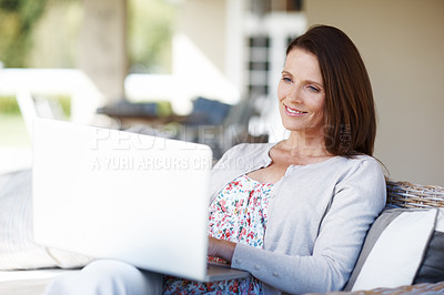 Buy stock photo An attractive woman working on a laptop while sitting outdoors