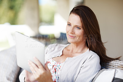 Buy stock photo An attractive woman reading something on her e-reader while sitting outdoors