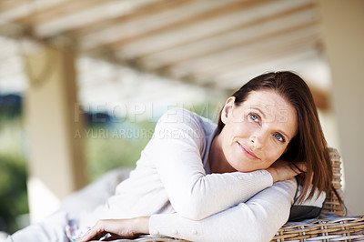 Buy stock photo An attractive woman relaxing on an outdoor chair and looking thoughtful