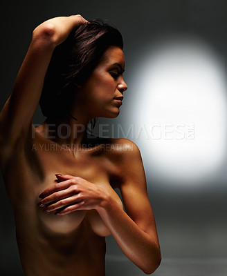 Buy stock photo Portrait of a naked young female covering her breast against dark background