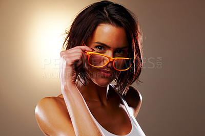 Buy stock photo Portrait, fashion and glasses with a young woman in studio on a gray background for vision or style. Trendy, eyewear and a confident model flirting while peeking over prescription frame lenses