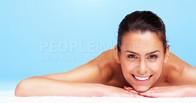 Buy stock photo Portrait of a pretty young woman lying against blue background