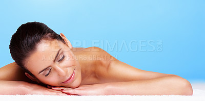 Buy stock photo Portrait of an attractive young woman lying against blue background
