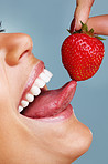 Detail shot of a seductive female licking a fresh strawberry