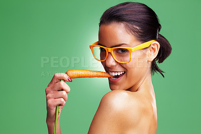 Buy stock photo Closeup portrait of a seductive woman wearing glasses and eating carrot against green background