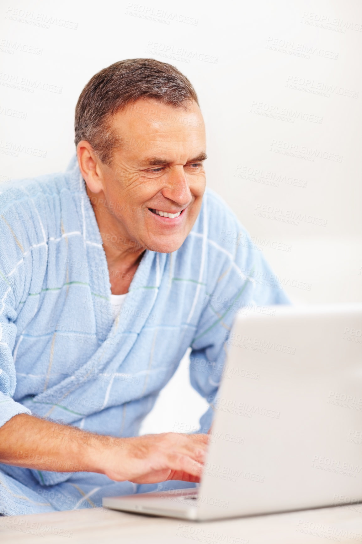 Buy stock photo Bathrobe, morning and mature happy man on laptop for email, social media or streaming subscription on sofa. Internet search, couch and senior person on computer, website or networking in living room.