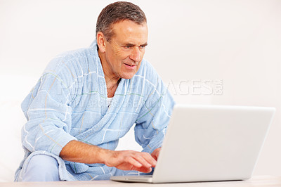 Buy stock photo Bathrobe, morning and mature happy man on computer for email, social media or streaming subscription on sofa. Internet search, couch and senior person on laptop, website or networking in living room.