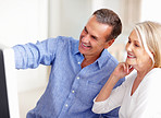 Mature couple with a cheerful man pointing at computer screen