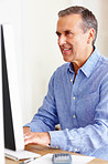 Smiling mature man calculating expenses using computer