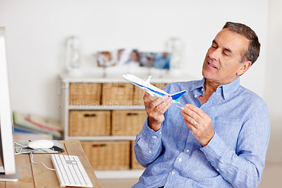 Buy stock photo Mature man, thinking and toy plane for travel, vacation and holiday planning with a smile at home. Happy, airplane model and retirement of a male person with confidence from trip and air traveling