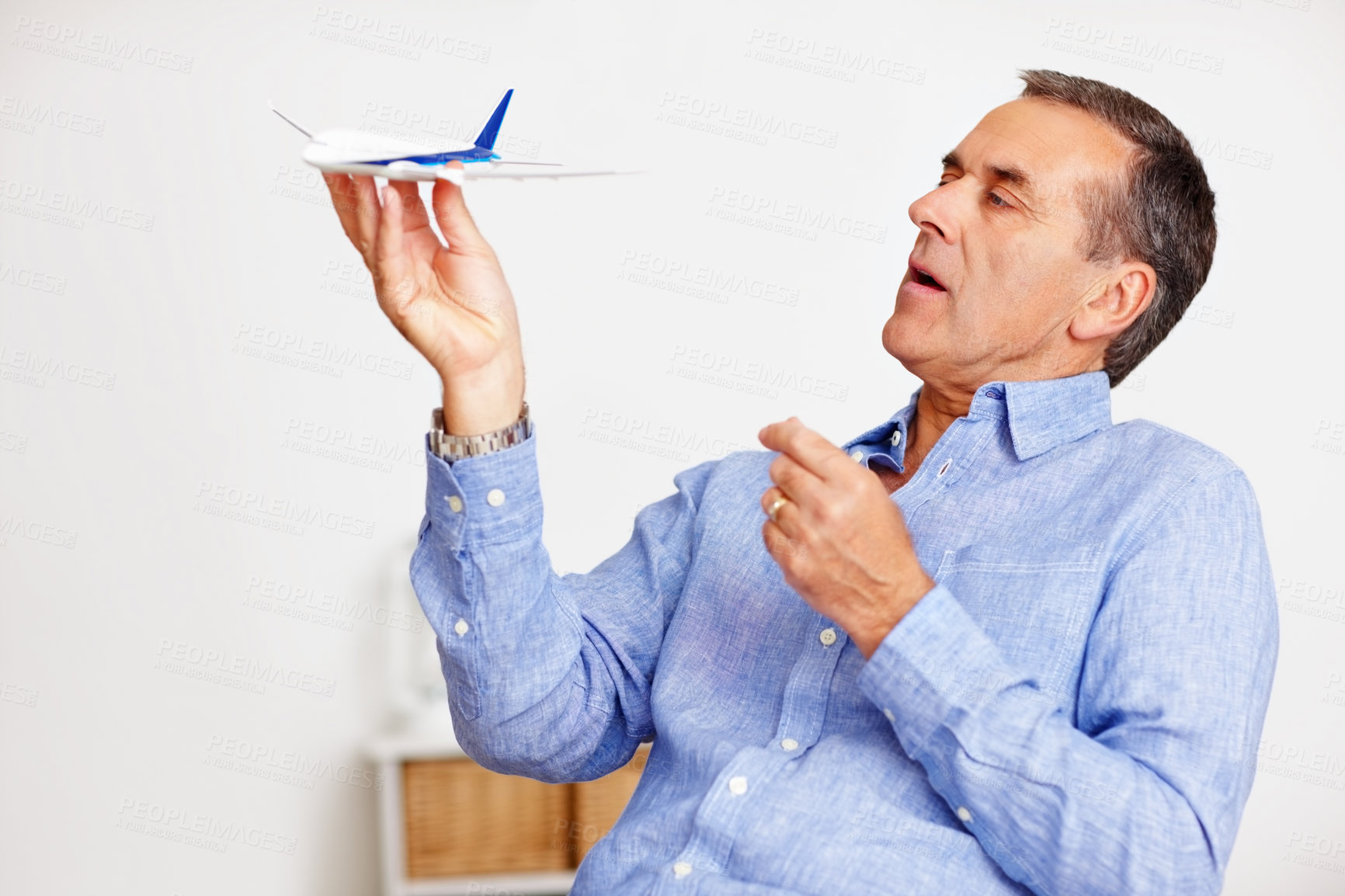 Buy stock photo Mature man, flying and toy plane for travel, vacation and holiday planning with a smile at home. Happy, airplane model and retirement of a male person with confidence from trip and air traveling