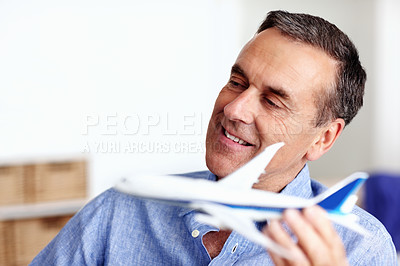 Buy stock photo Business man, travel and toy plane for flight, vacation and holiday planning with a smile at home. Happy, airplane model and retirement of a male person with confidence from trip and air traveling