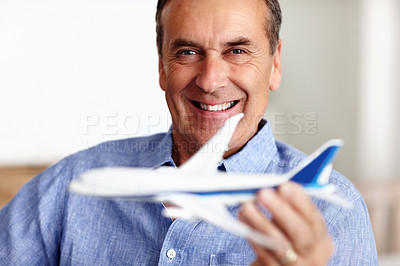 Buy stock photo Mature man, portrait and toy plane for travel, vacation and holiday planning with a smile at home. Happy, airplane model and retirement of a male person with confidence from trip and air traveling