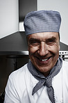 Cheerful senior chef in front of vent hood