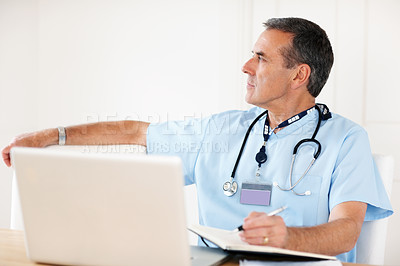 Buy stock photo Portrait of a senior doctor noting his schedule with laptop on desk