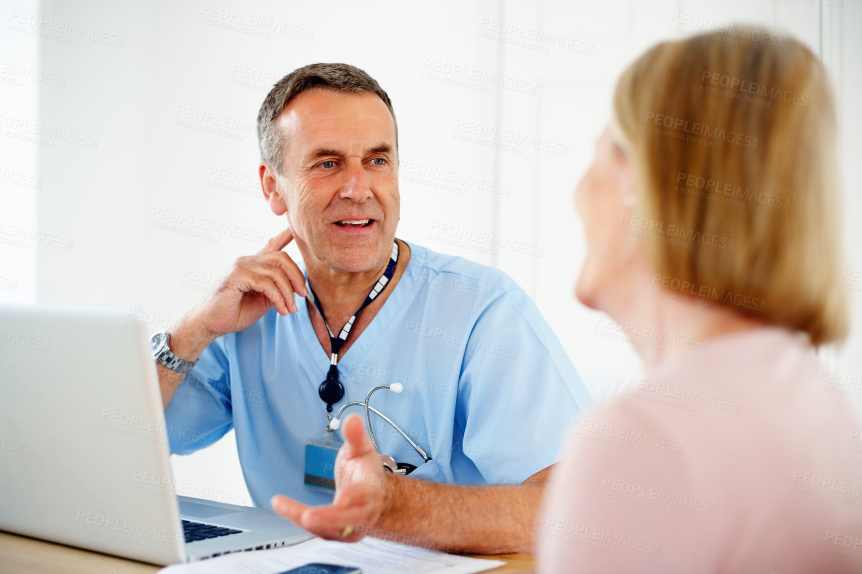 Buy stock photo Portrait of a mature doctor talking with female patient sitting at desk