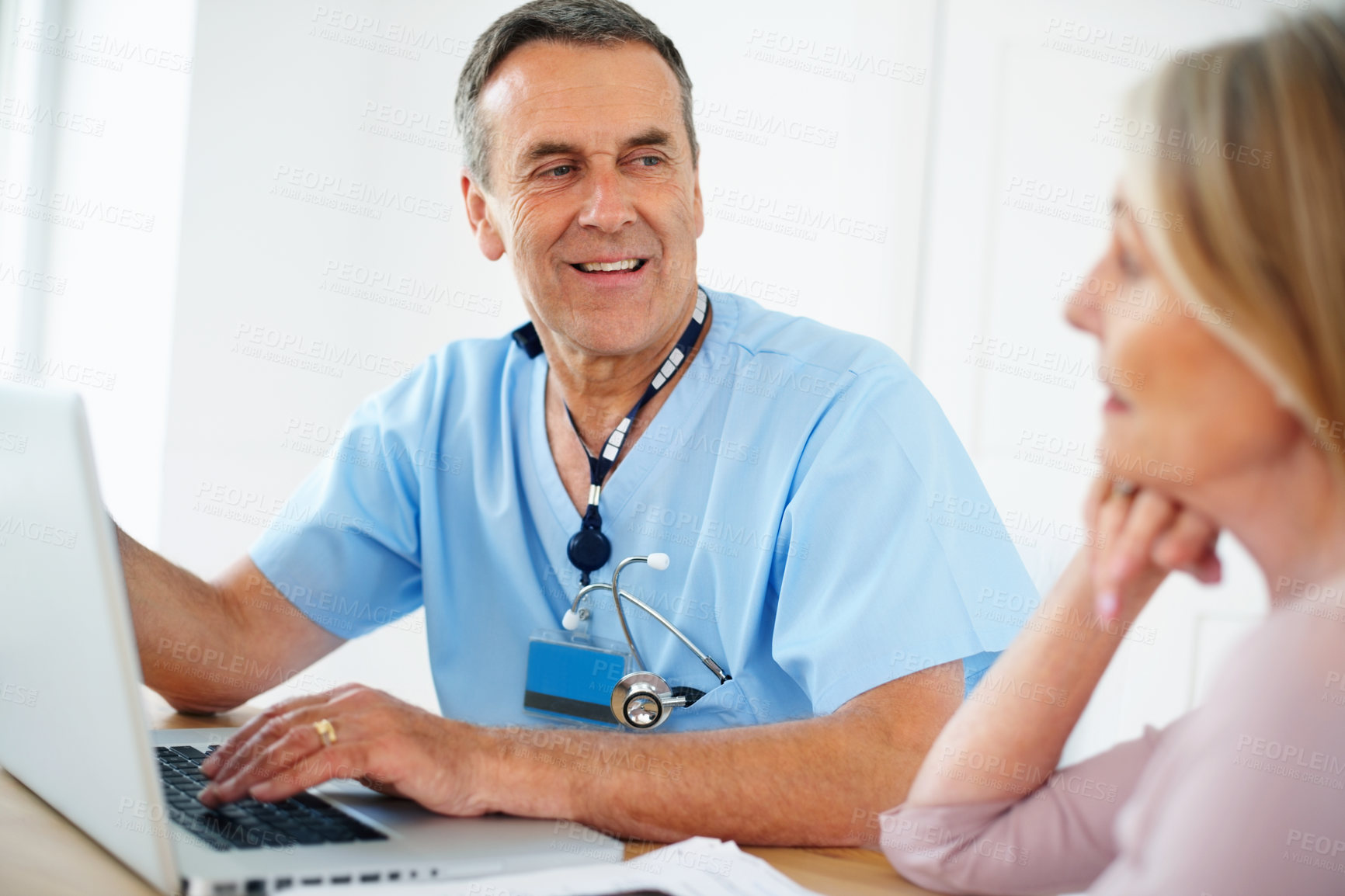 Buy stock photo Portrait of a male doctor discussing with female patient using laptop at clinic