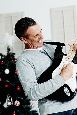 Buy stock photo Mature man, guitar and happy for Christmas with gift, excited and fun in living room. Male musician, smile and instrument in lounge for music, creativity or celebration with happiness at home