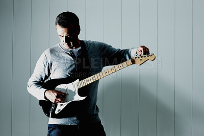 Buy stock photo Guitar, tuning and man playing music for creative, art or musician career by wall at home. Artist, rock and male guitarist with electric string instrument practicing for show, performance or concert.