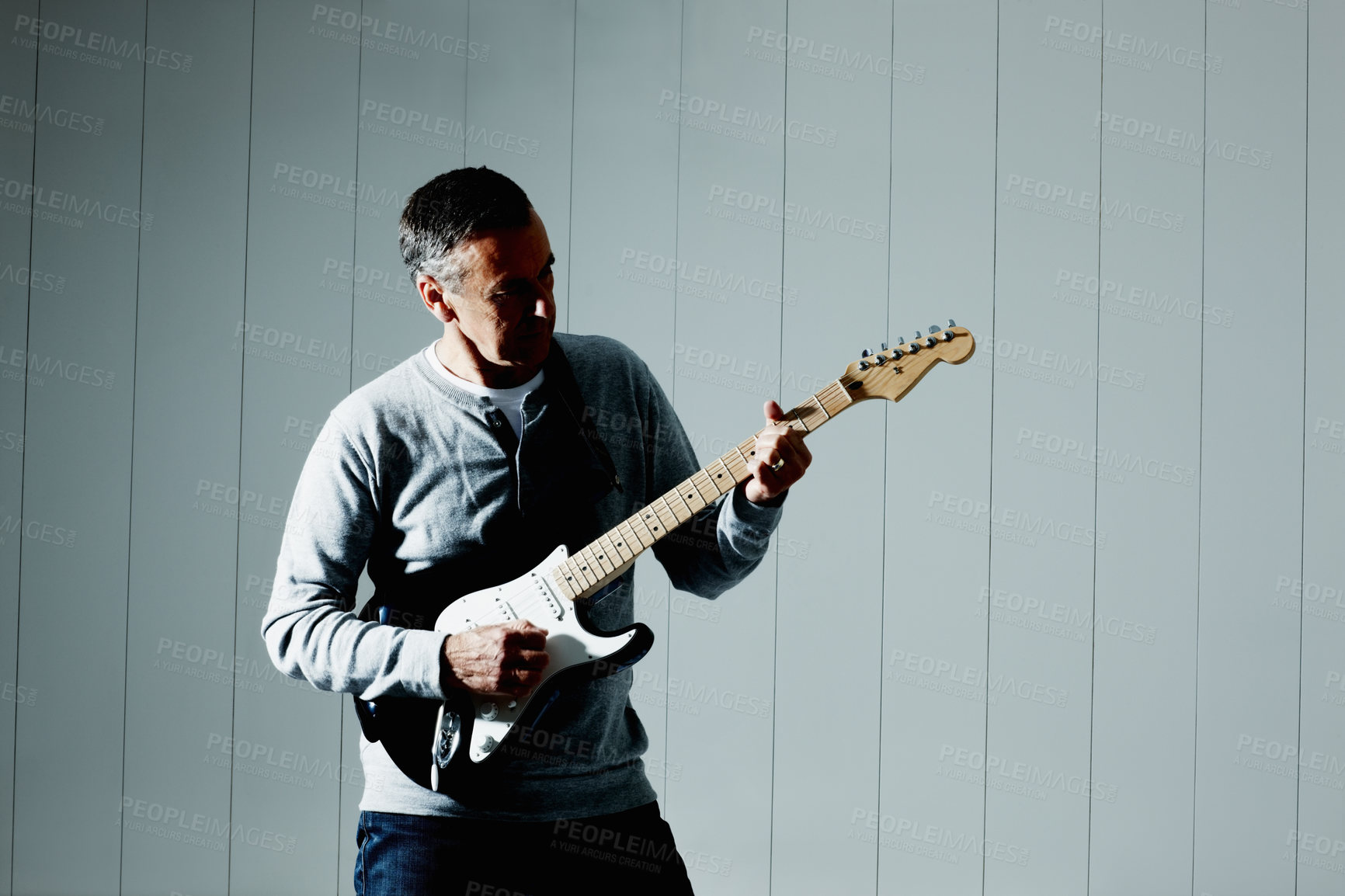 Buy stock photo Musician, tuning and man playing guitar for creative, art or musical career by wall at home. Artist, rock and guitarist with electric string instrument practicing for show, performance or concert.