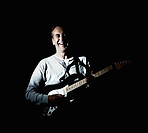 Cheerful mature man playing guitar against black background