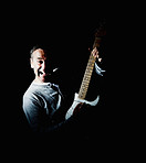 Mature man playing an acoustic guitar against black background