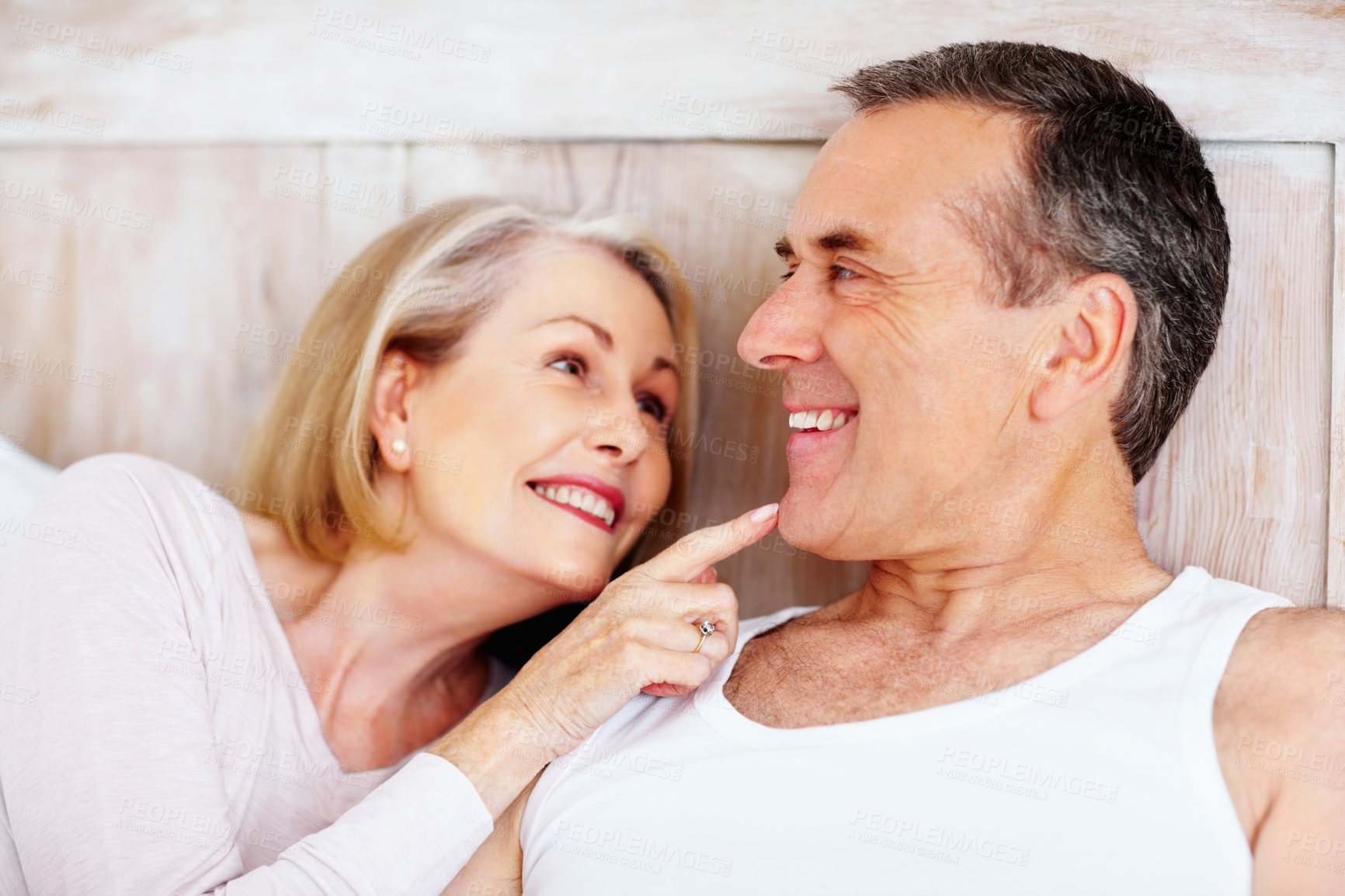 Buy stock photo Mature couple, happy and romance in bed at house for relax, love and retirement together with trust and care. Man, woman and cuddle in bedroom for marriage, loyalty or break on weekend with smile