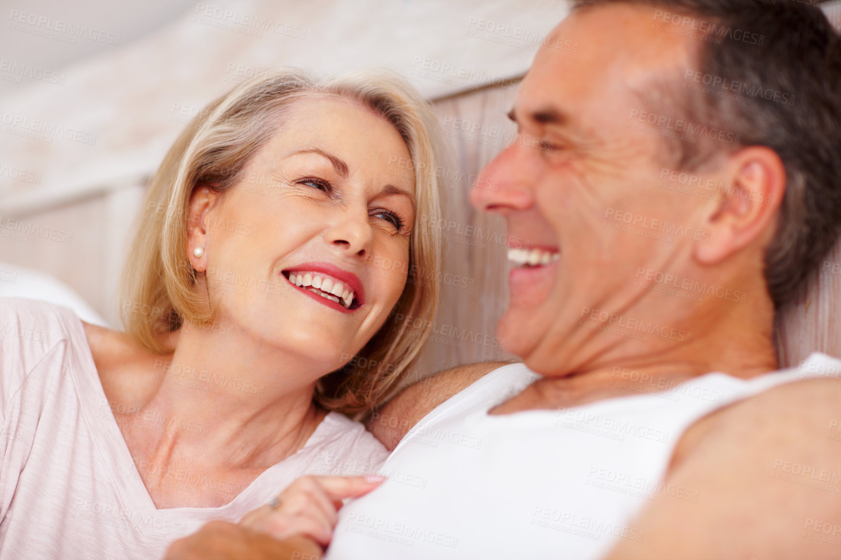 Buy stock photo Mature couple, happy and romantic in bed at house for relax, love and retirement together with trust and care. Man, woman and flirt in bedroom for marriage, loyalty and playful on weekend with smile