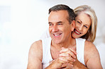 Cheerful mature woman embracing husband from back against white