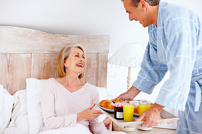 Buy stock photo Portrait of loving mature man serving breakfast to his wife in bed