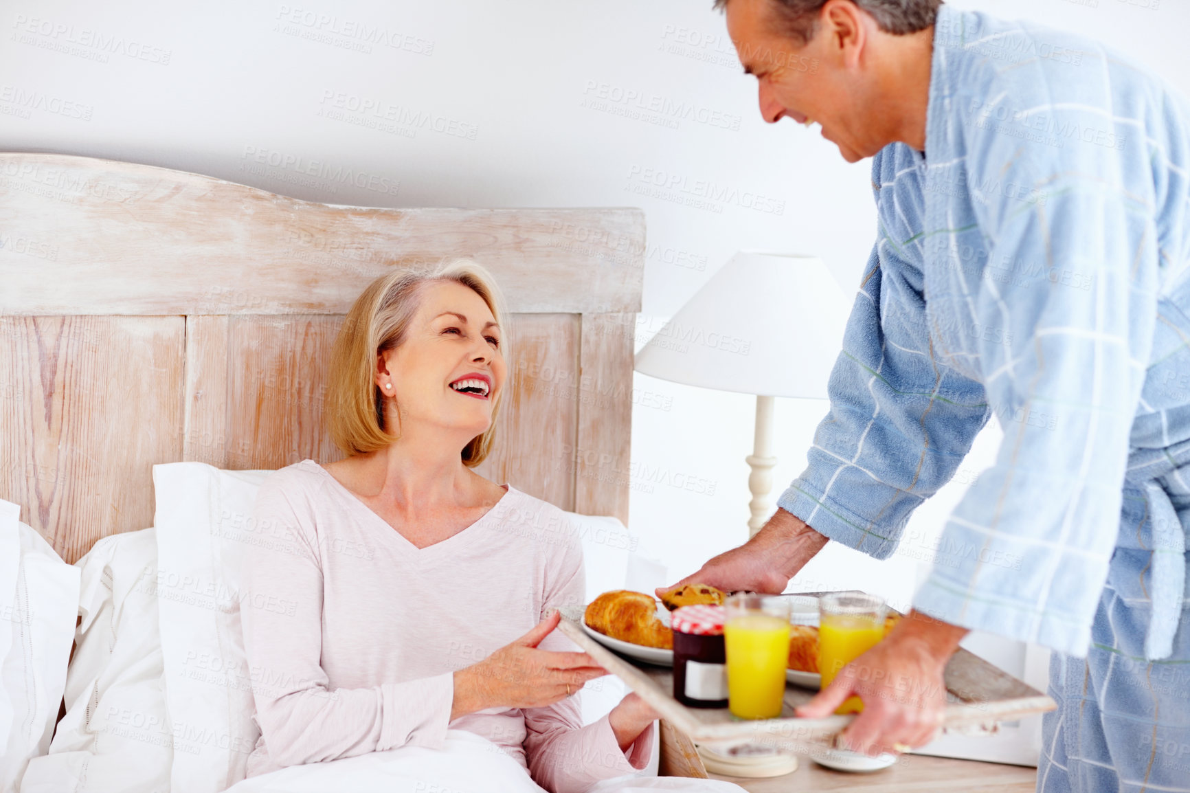 Buy stock photo Portrait of loving mature man serving breakfast to his wife in bed