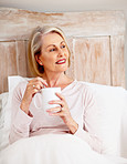 Smiling mature woman holding coffee mug in bed