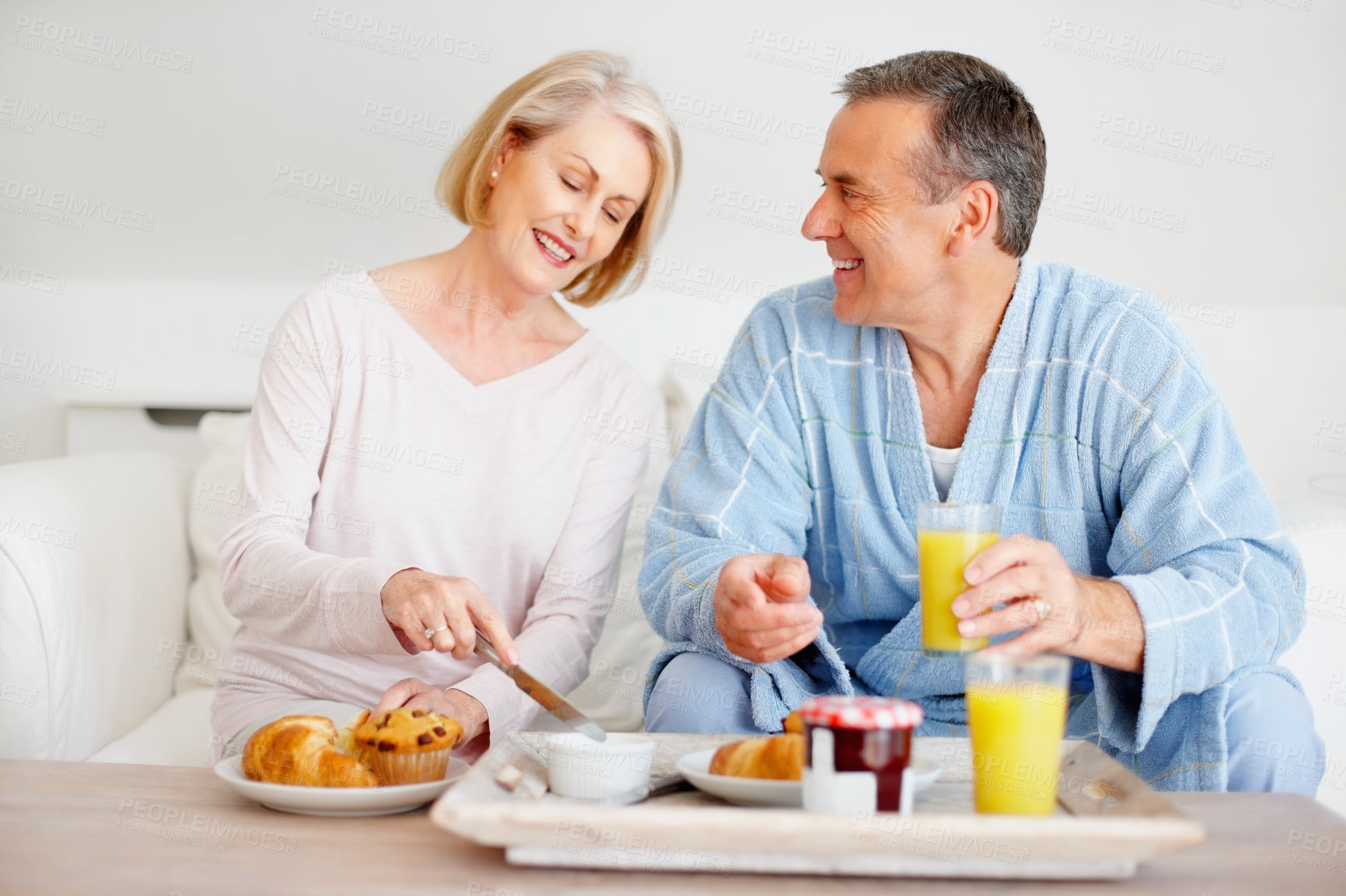 Buy stock photo Mature couple, smile and breakfast together on sofa with bonding, diet nutrition and support in home. Happy, man and woman with morning meal, healthy food and romantic time for love relationship